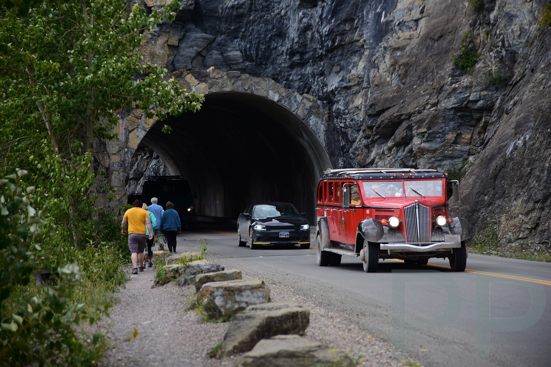 Red Bus exiting a mountain tunnel in Glacier National Park