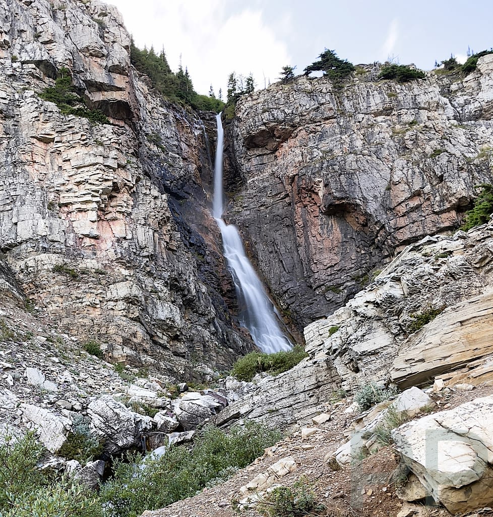 Apikuni Falls waterfall cascading down a steep cliff in the Many Glacier area of Glacier National Park