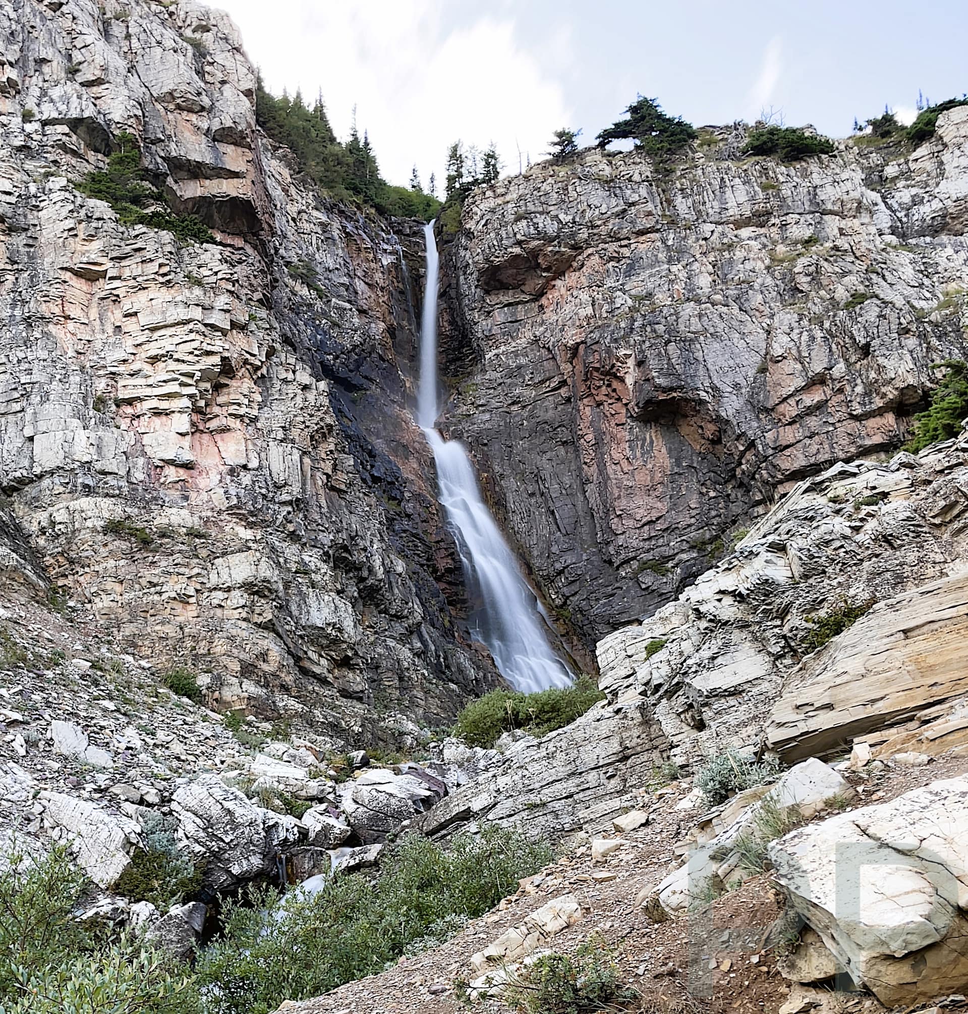 Apikuni Falls waterfall cascading down a steep cliff in the Many Glacier area of Glacier National Park