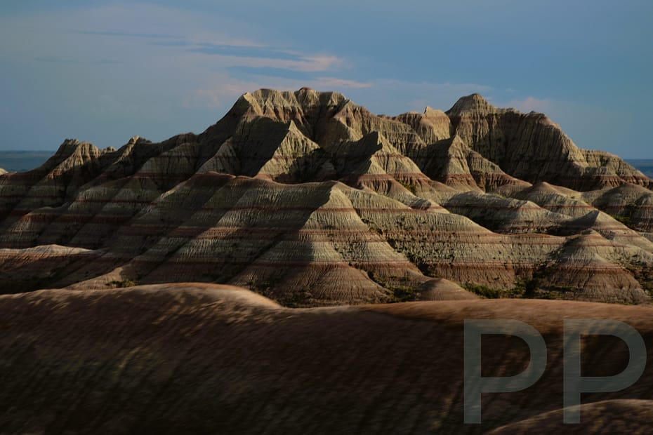 Layered cliffs and ridges of Badlands National Park glowing gold and pink at sunrise.