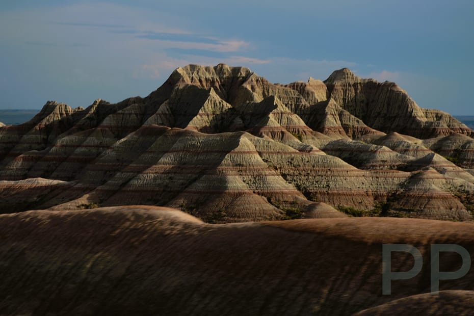Layered cliffs and ridges of Badlands National Park glowing gold and pink at sunrise.