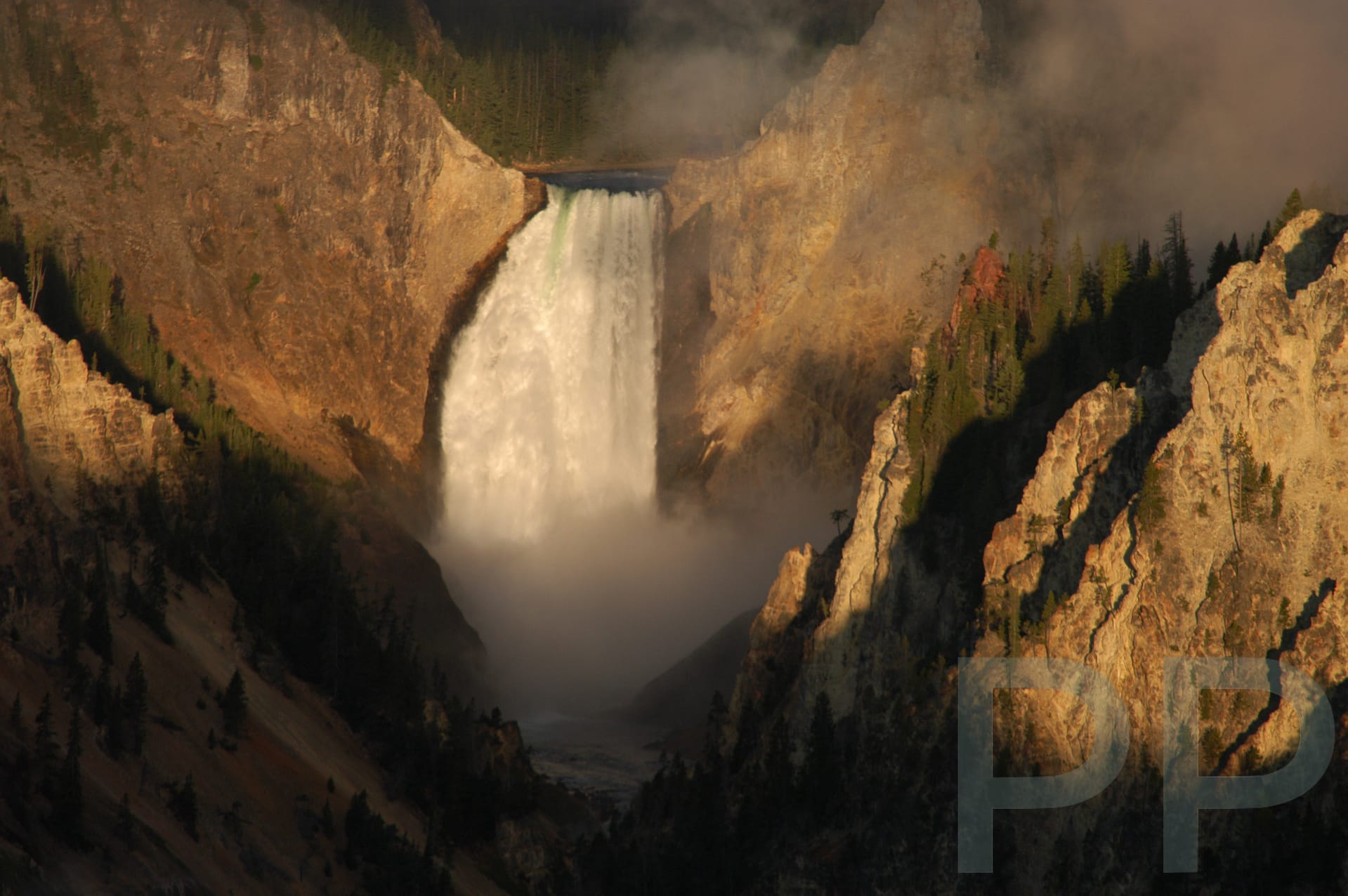 Lower Yellowstone Falls at sunrise with mist and golden light in Yellowstone National Park