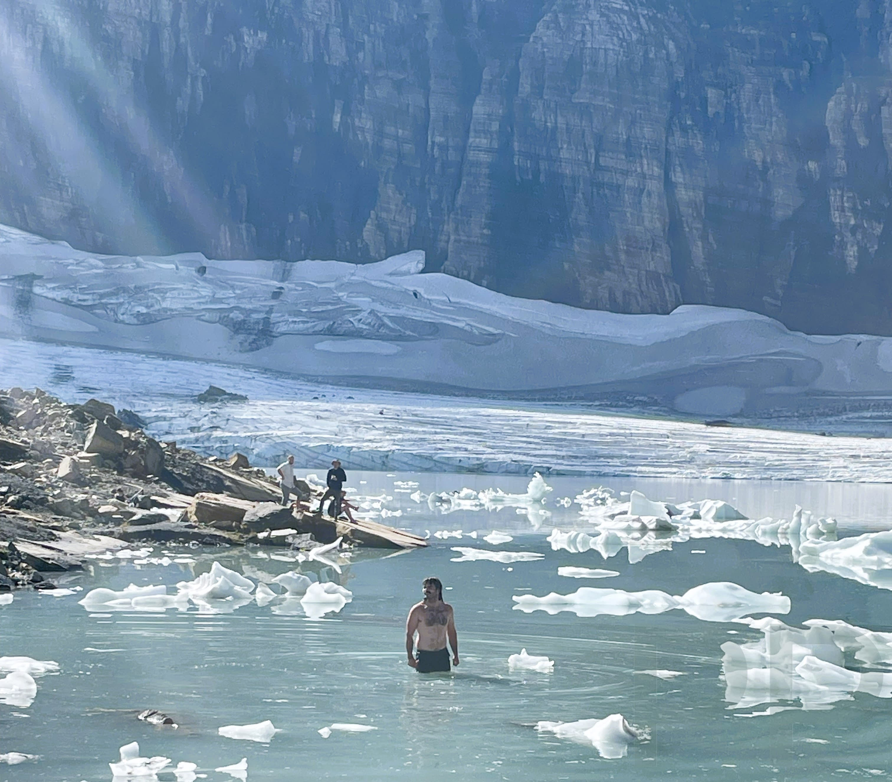 A man swims in icy water at the base of Grinnell Glacier in National Park