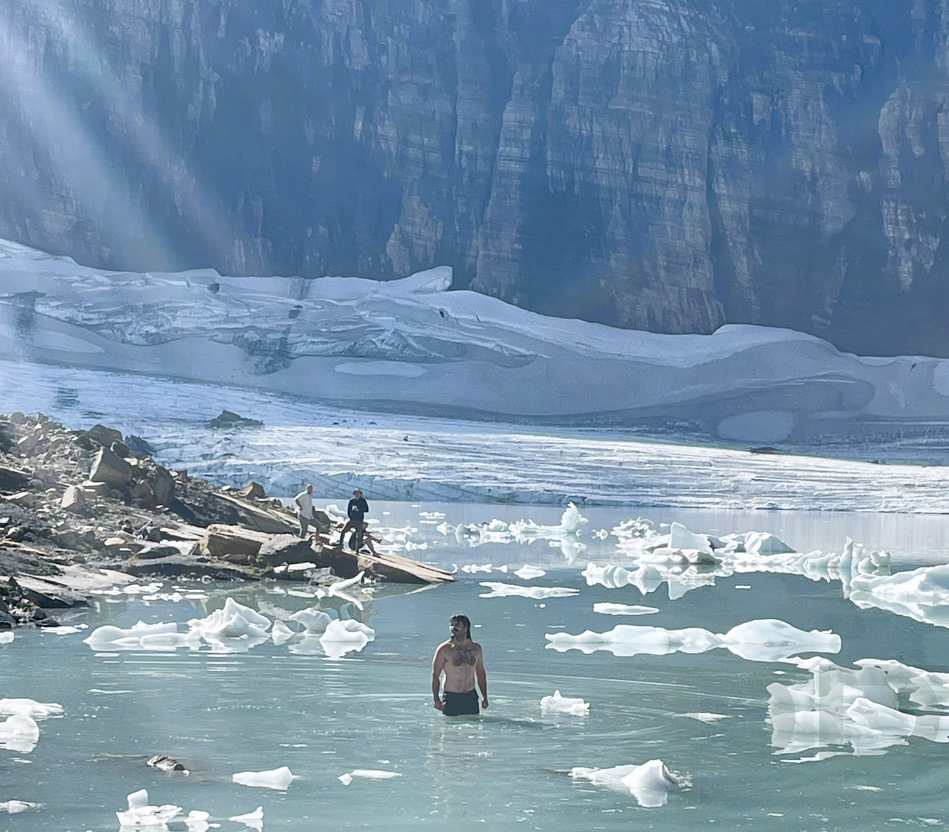 A man swims in icy water at the base of Grinnell Glacier in National Park