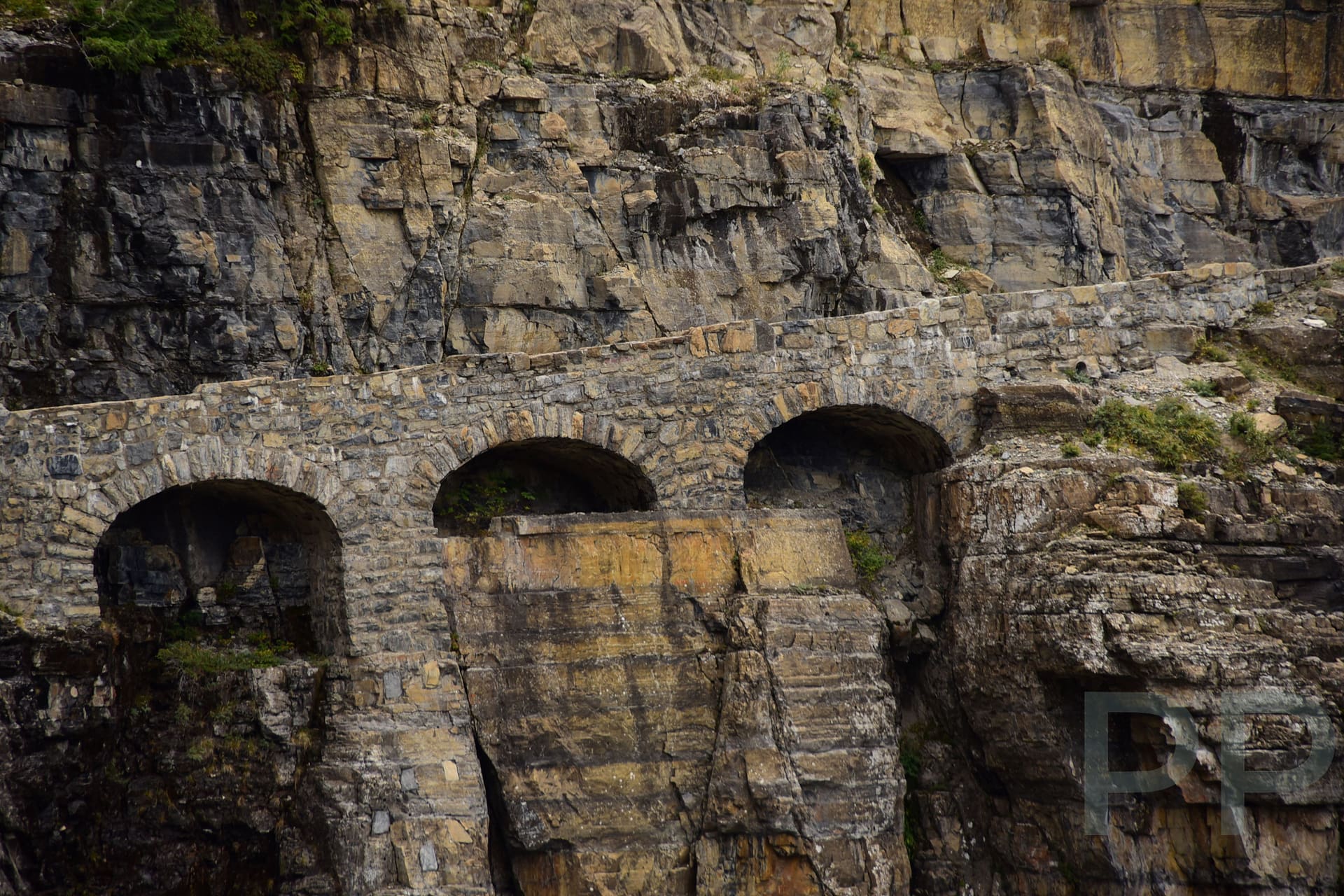Triple Arches supporting Going-to-the-Sun Road along a steep mountainside in Glacier National Park