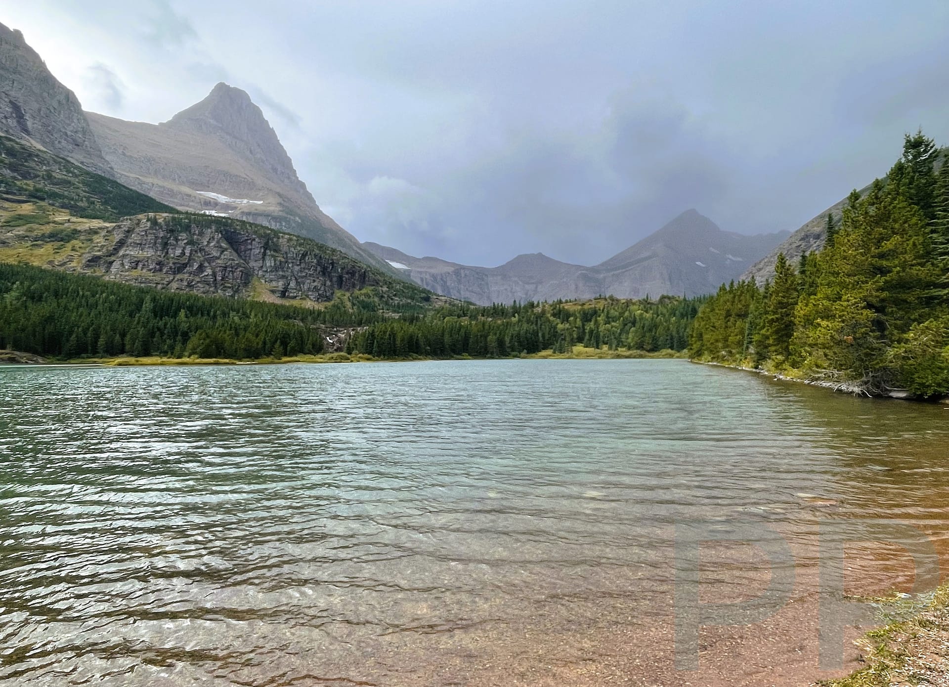 Redrock Lake with mountains and approaching storm clouds in the Many Glacier area of Glacier National Park