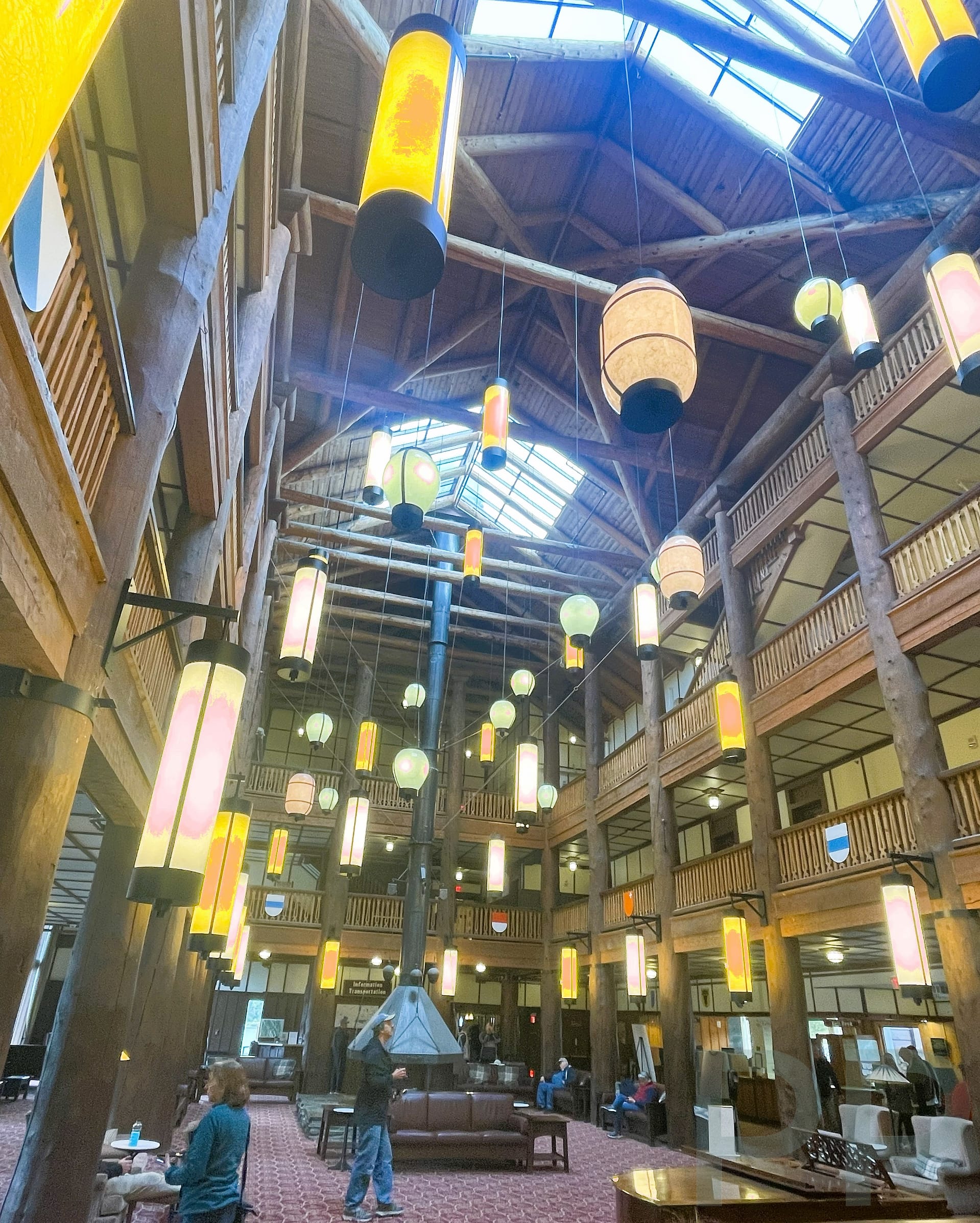 Interior of Many Glacier Hotel lobby with timber beams, hanging lanterns, and a vaulted ceiling in Glacier National Park