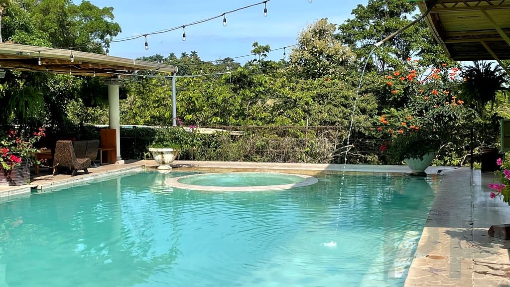 Thermal pool with surrounding greenery, lounge seating, and garden views at Termales de Santa Teresa hot springs, Ruta de las Flores, El Salvador.