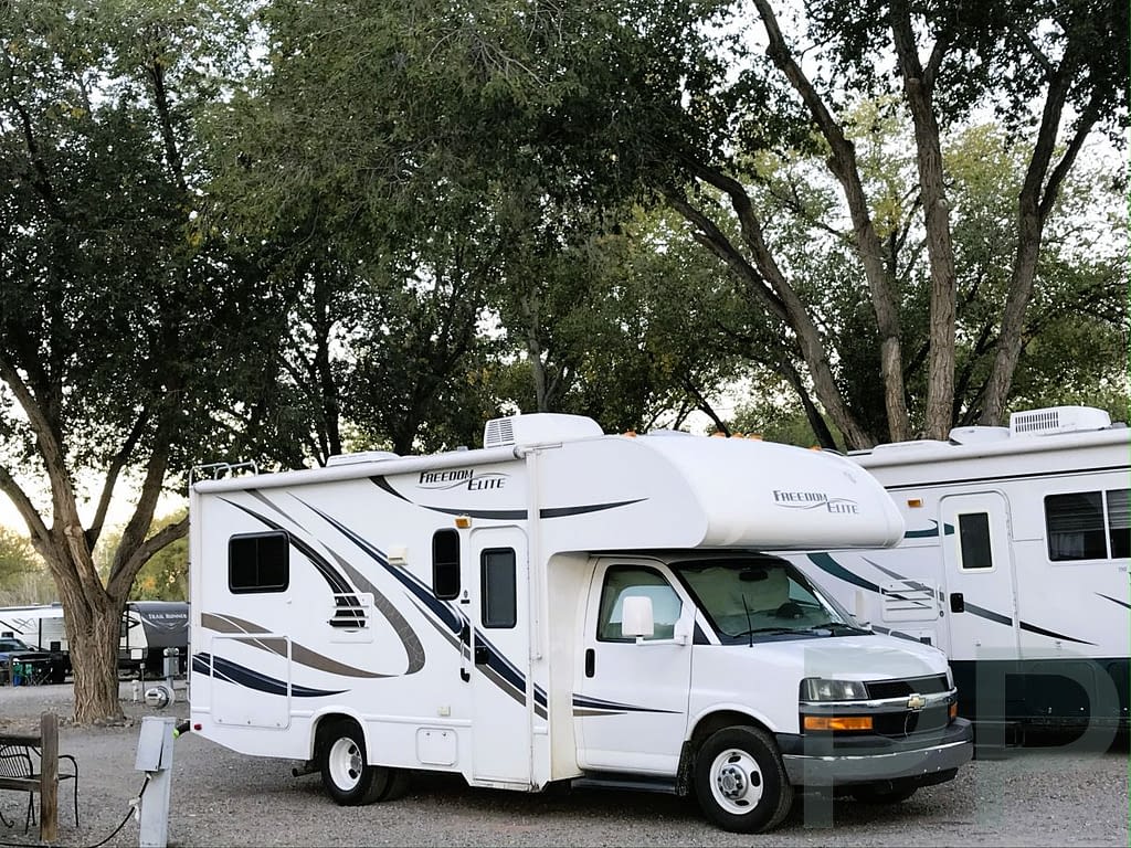 RV connected to water and electricity hookups at a campground.