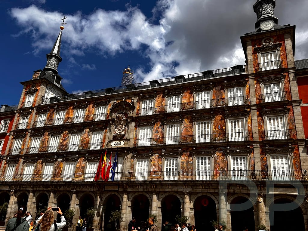 Painted building façade on Plaza Mayor in Madrid with flags, murals, and a “Plaza Mayor” plaque.