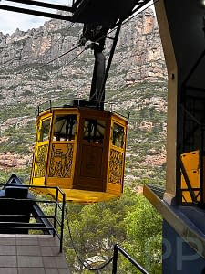 Aeri de Montserrat cable car arriving at the station with rocky cliffs in the background