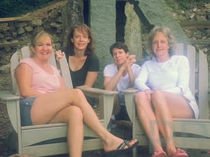 Four friends relaxing in Adirondack chairs outside the Len Foote Hike Inn after completing the hike from Amicalola Falls.