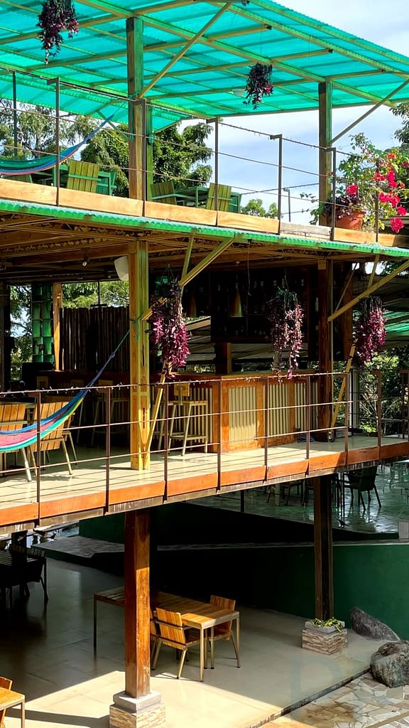 Two-story restaurant with open-air terraces, hanging plants, and hammocks at Termales de Santa Teresa, Ruta de las Flores, El Salvador.
