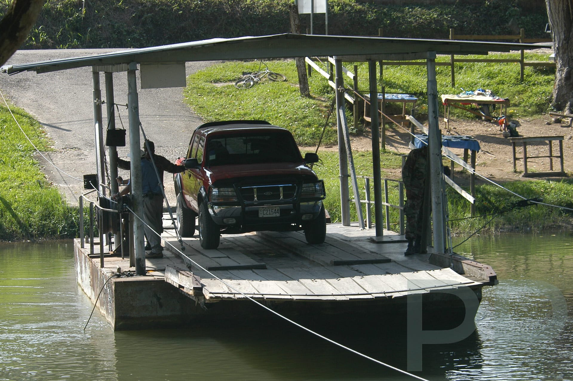 Vehicle crossing a river on a small ferry as part of travel logistics