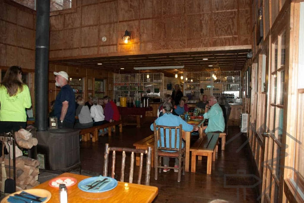 Hikers dining together at long wooden tables in the Len Foote Hike Inn dining room at Amicalola Falls State Park.