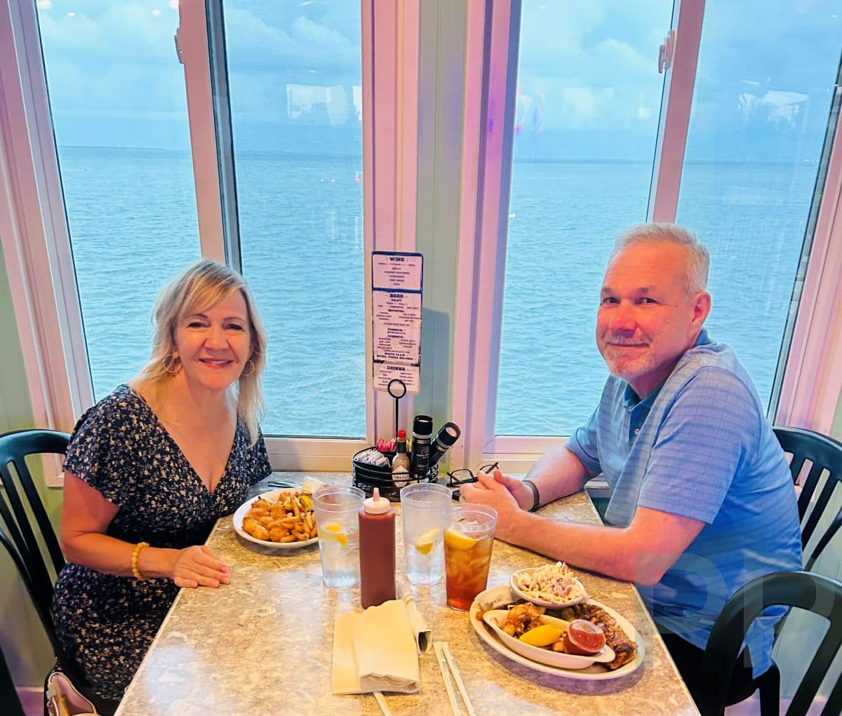 Couple dining at a waterfront restaurant on Anna Maria Island with Gulf view through windows.