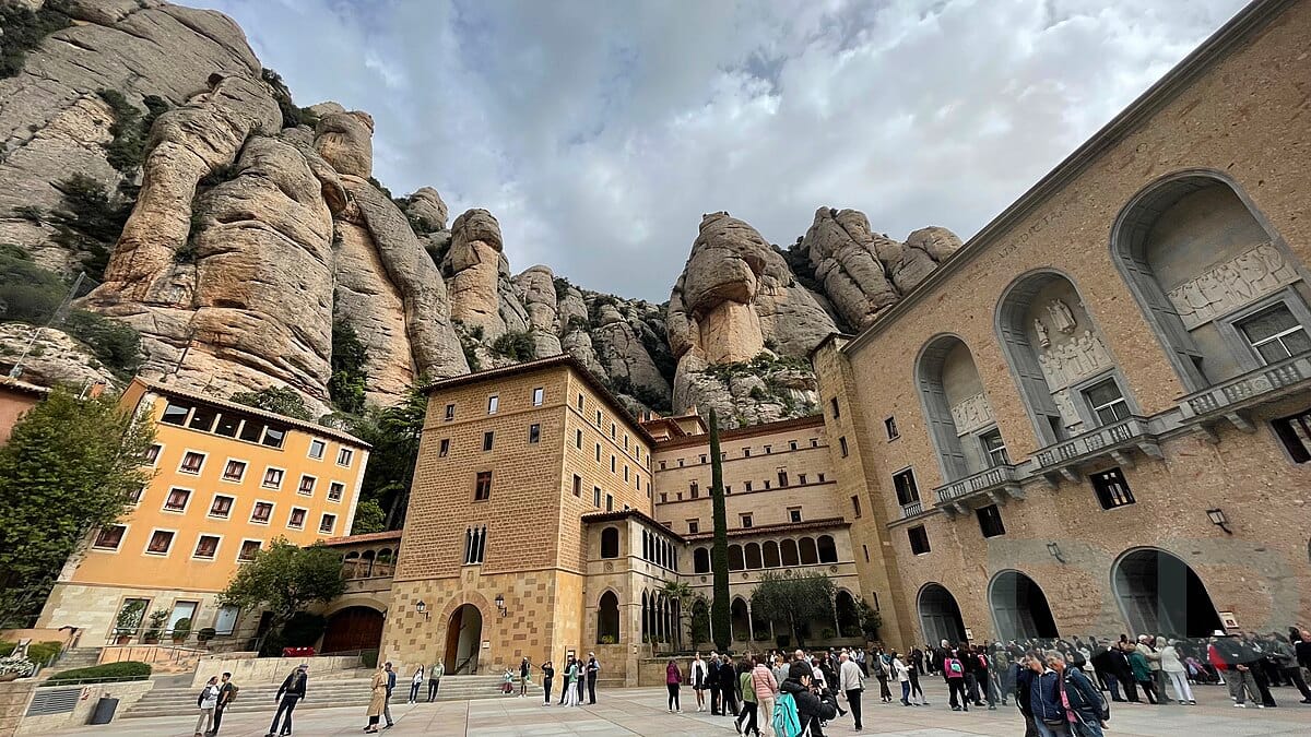 Wide view of Montserrat Monastery with towering rock formations rising behind it