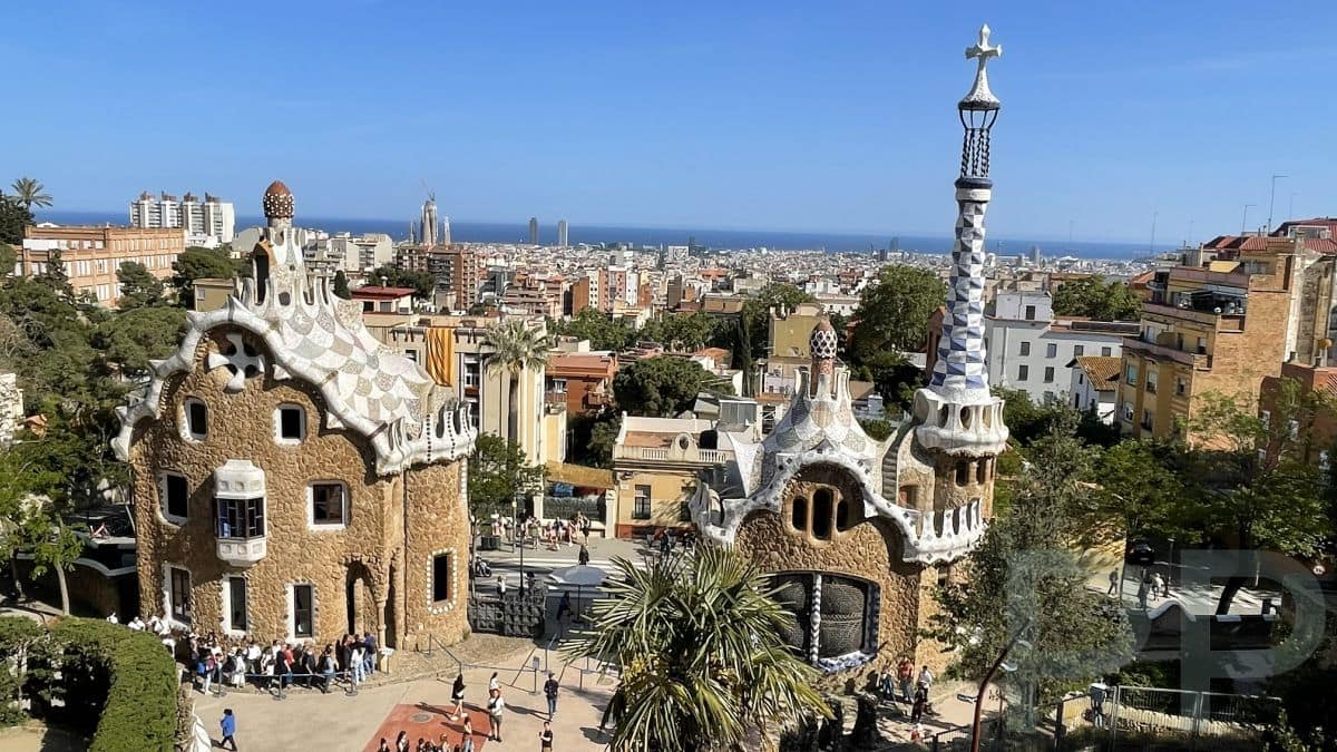 View from Park G&uuml;ell in Barcelona showing Antoni Gaud&iacute;&rsquo;s mosaic gatehouses with the city and Mediterranean Sea in the background.