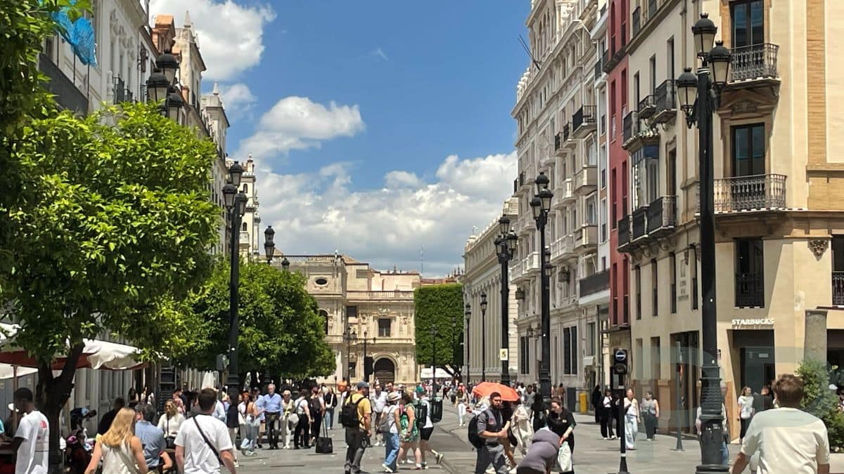 Pedestrian street in Seville with people walking between historic buildings