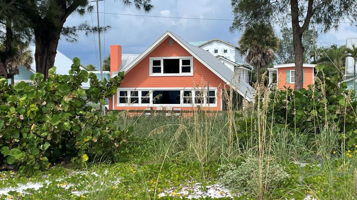 Orange beach cottage surrounded by sea grapes and dunes on Anna Maria Island.