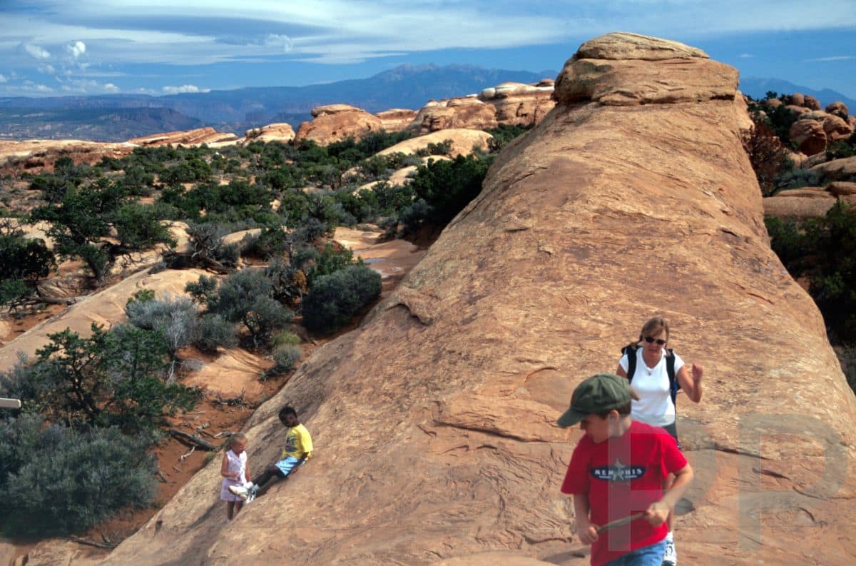 Children hiking narrow sandstone fin on Devils Garden Trail Arches National Park