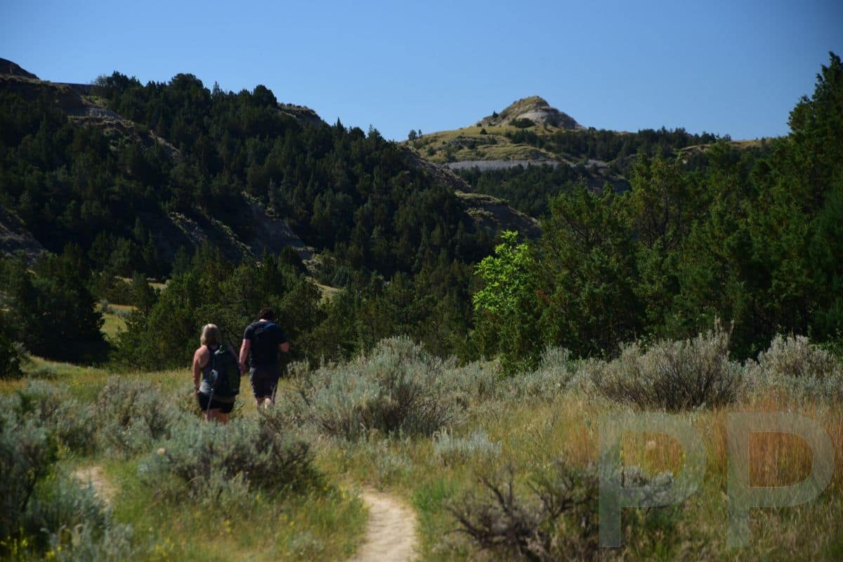 Hikers standing along a narrow ridgeline trail in Theodore Roosevelt National Park North Unit