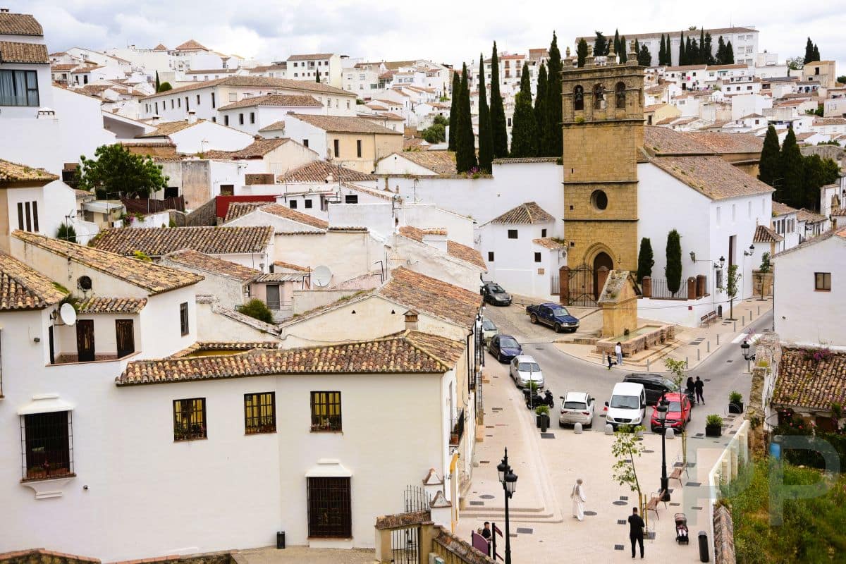 Panoramic view of Ronda&rsquo;s old town with whitewashed houses, terracotta rooftops, and a historic stone church tower.