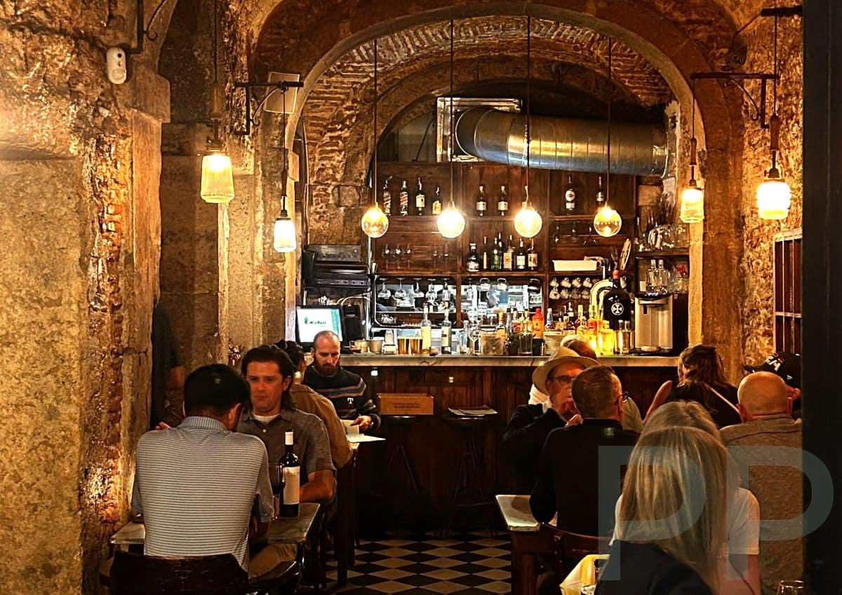 Interior of Restaurante El Vicente in Bairro Alto, Lisbon, with stone arches, small tables, and a warm, intimate atmosphere.