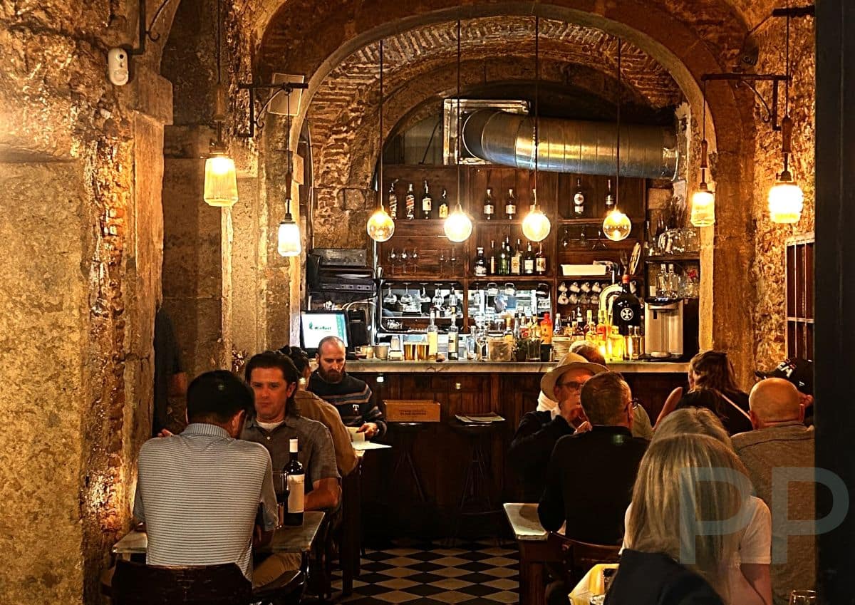 Interior of Restaurante El Vicente in Bairro Alto, Lisbon, with stone arches, small tables, and a warm, intimate atmosphere.