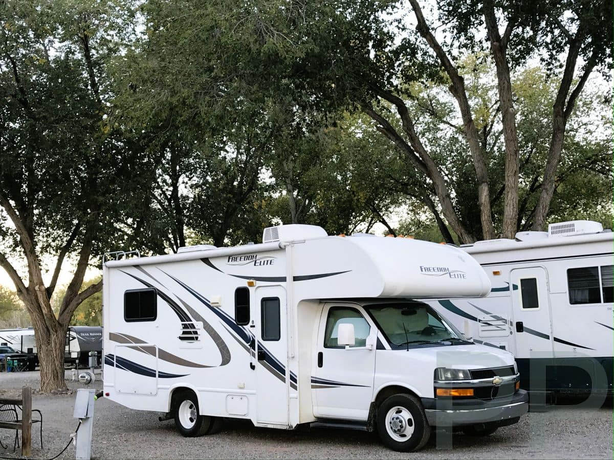 RV connected to water and electricity hookups at a campground.