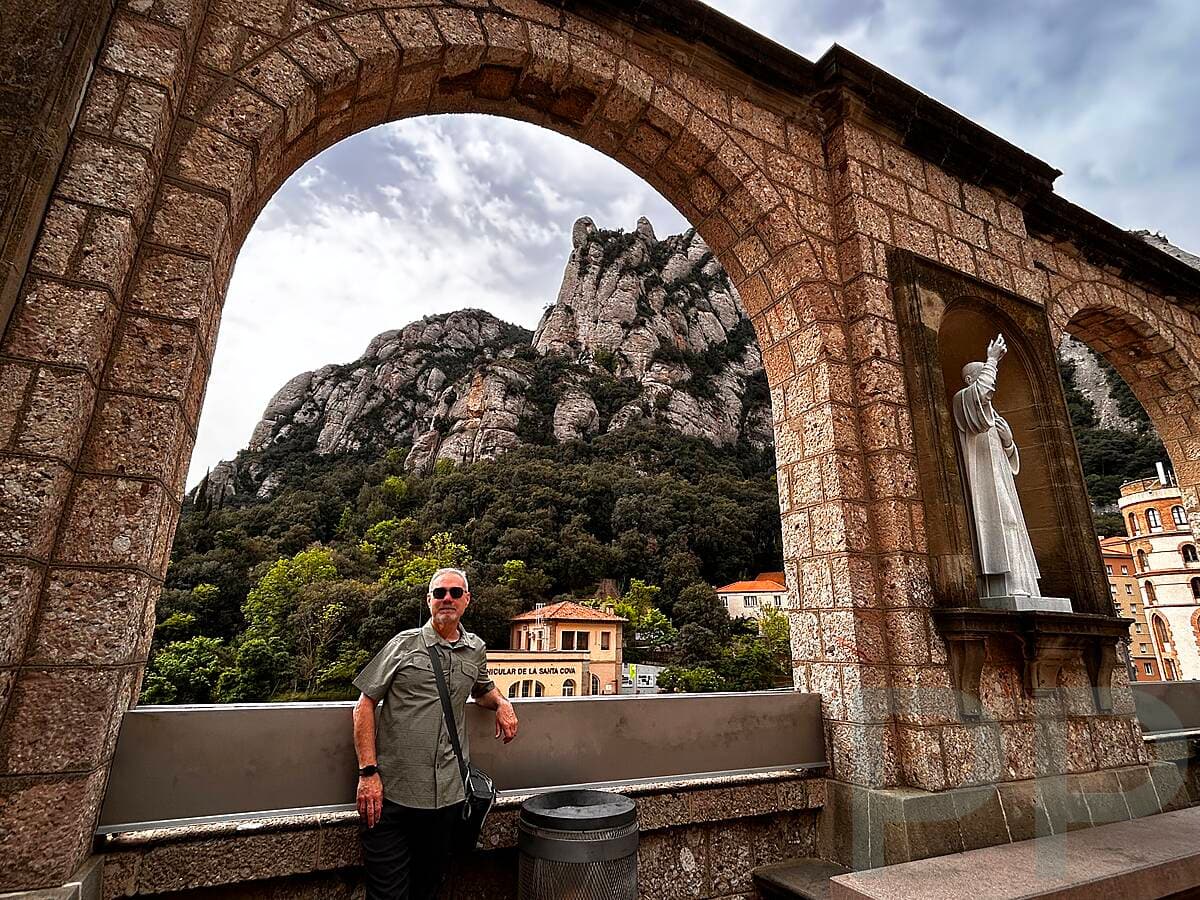 A man standing in a stone viewpoint overlooking the mountains and countryside at Montserrat
