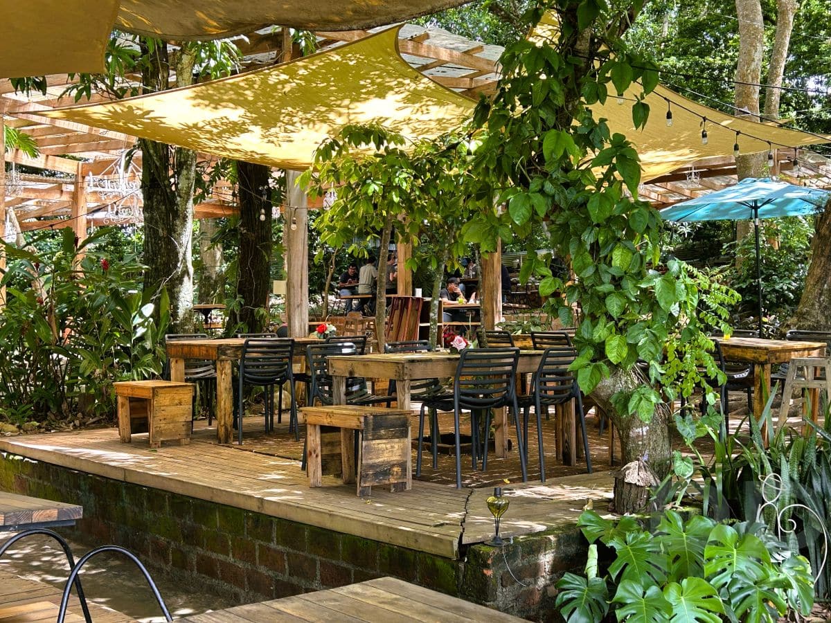 Shaded outdoor dining area at Casa 1800 in Suchitoto, El Salvador, set among trees and lush greenery