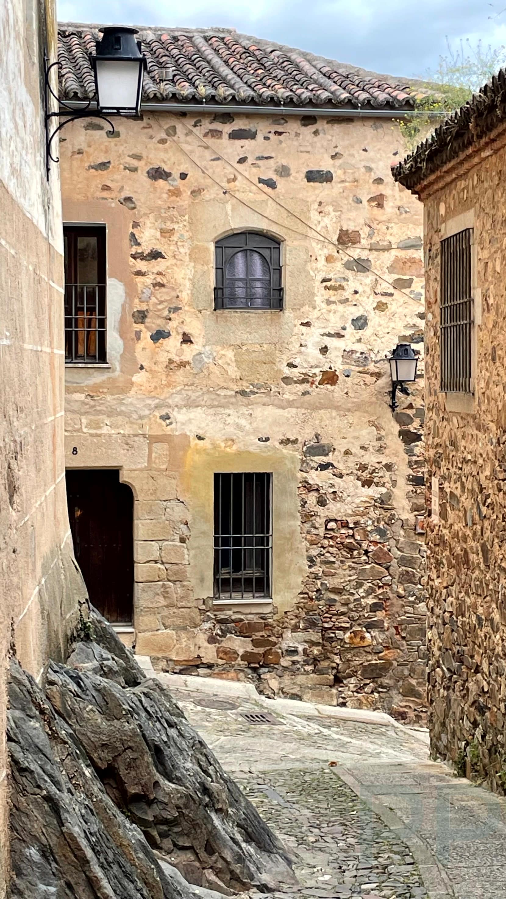 Quiet cobblestone streets winding through the medieval center of C&aacute;ceres, Spain.