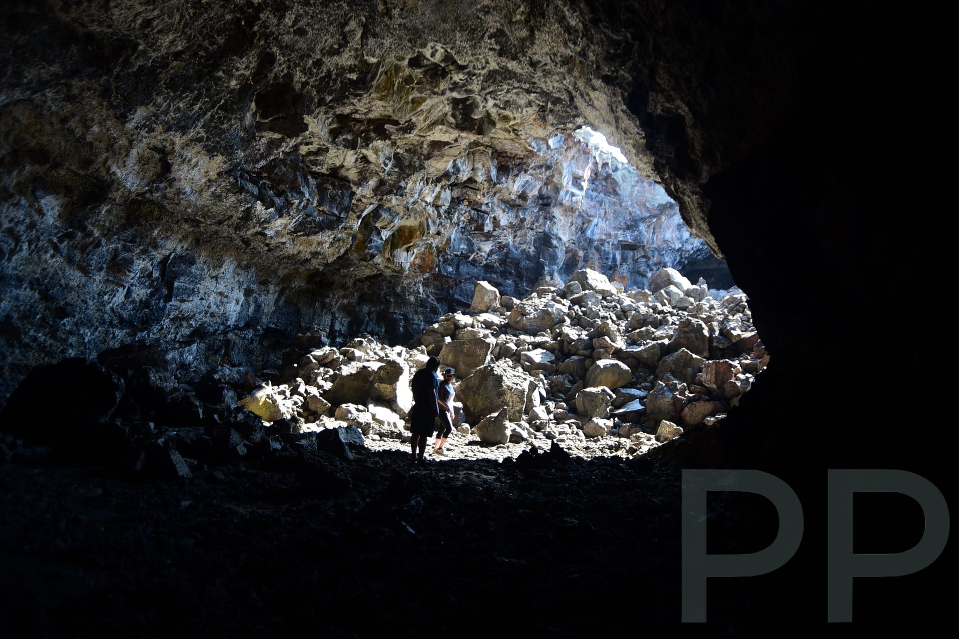 Interior of a lava tube cave with rocky walls and natural light entering from an opening