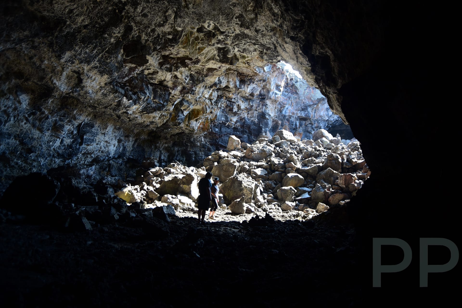 Interior of a lava tube cave with rocky walls and natural light entering from an opening