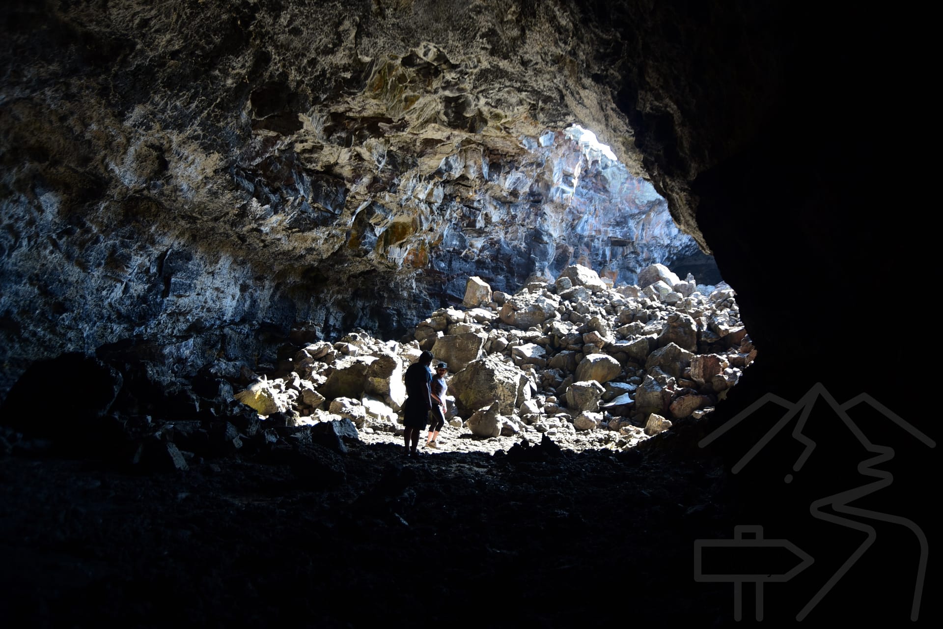 Interior of a lava tube cave with rocky walls and natural light entering from an opening