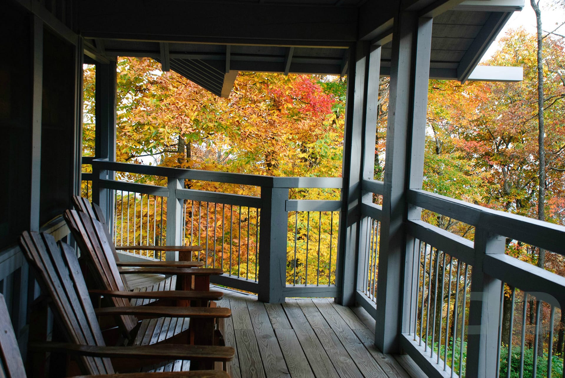 Porch with wooden chairs overlooking colorful fall leaves at the Len Foote Hike Inn in North Georgia.
