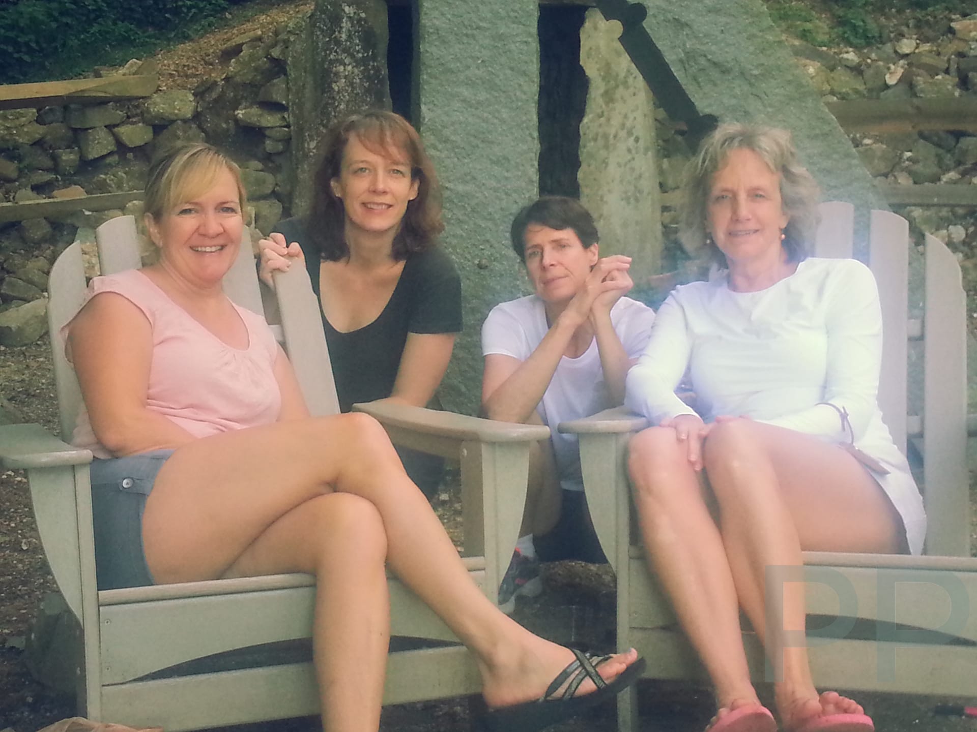 Four friends relaxing in Adirondack chairs outside the Len Foote Hike Inn after completing the hike from Amicalola Falls.