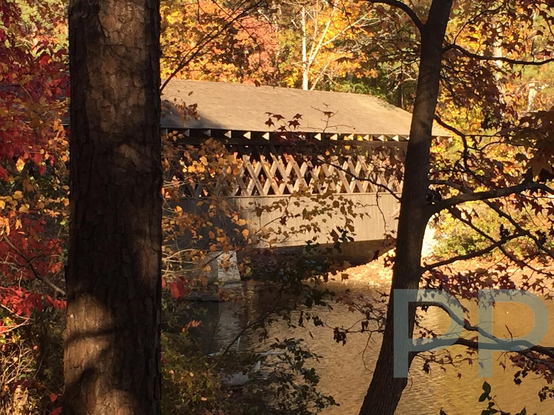 Historic covered bridge surrounded by autumn leaves at Stone Mountain Park.