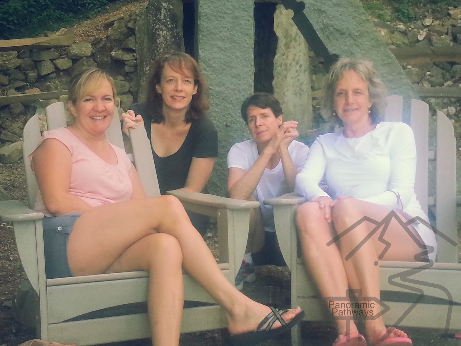 Four friends relaxing in Adirondack chairs outside the Len Foote Hike Inn after completing the hike from Amicalola Falls.
