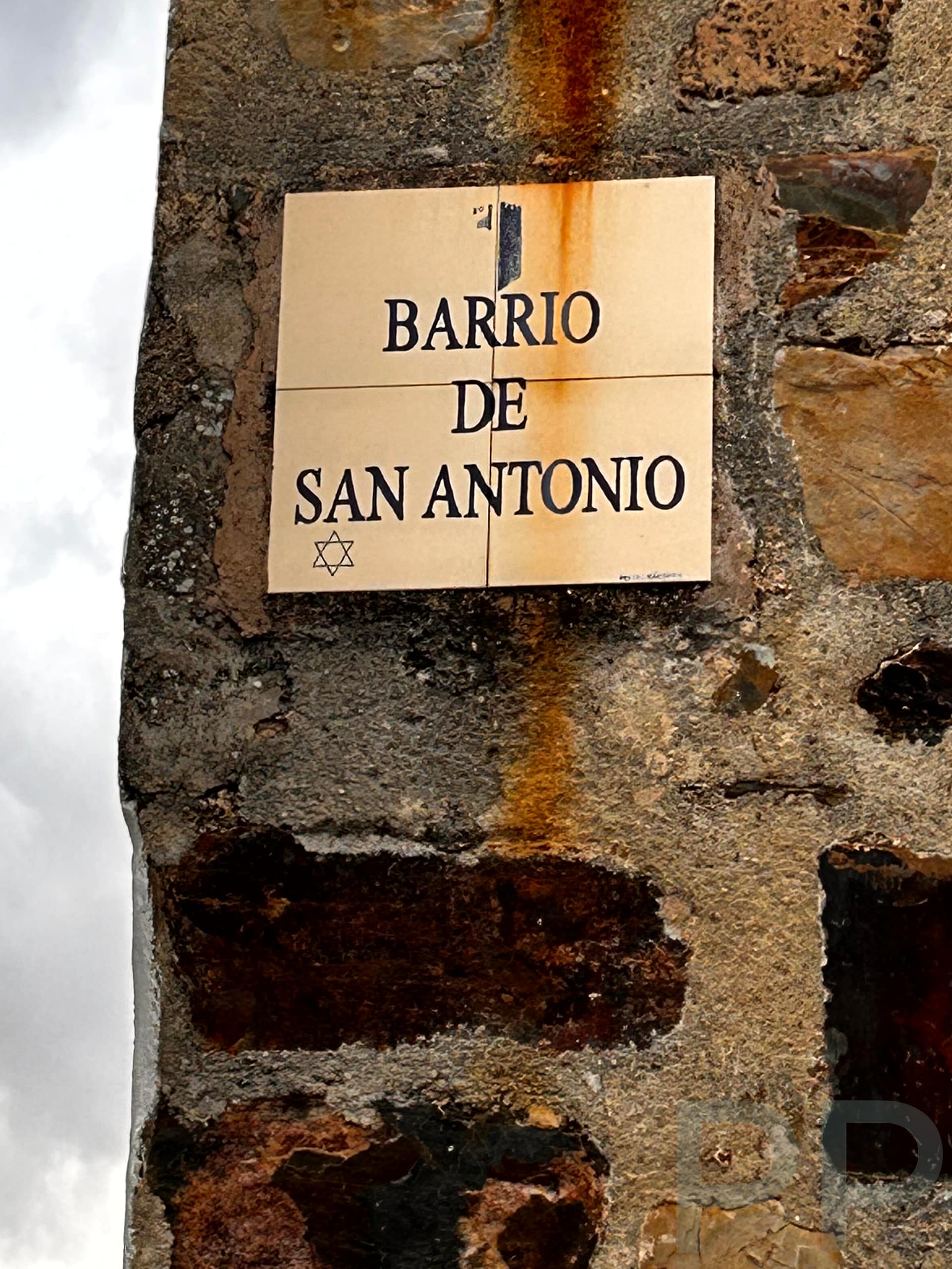 Sign marking the entrance to Barrio de San Antonio in Cáceres, featuring a Star of David to signify the historic Jewish Quarter.