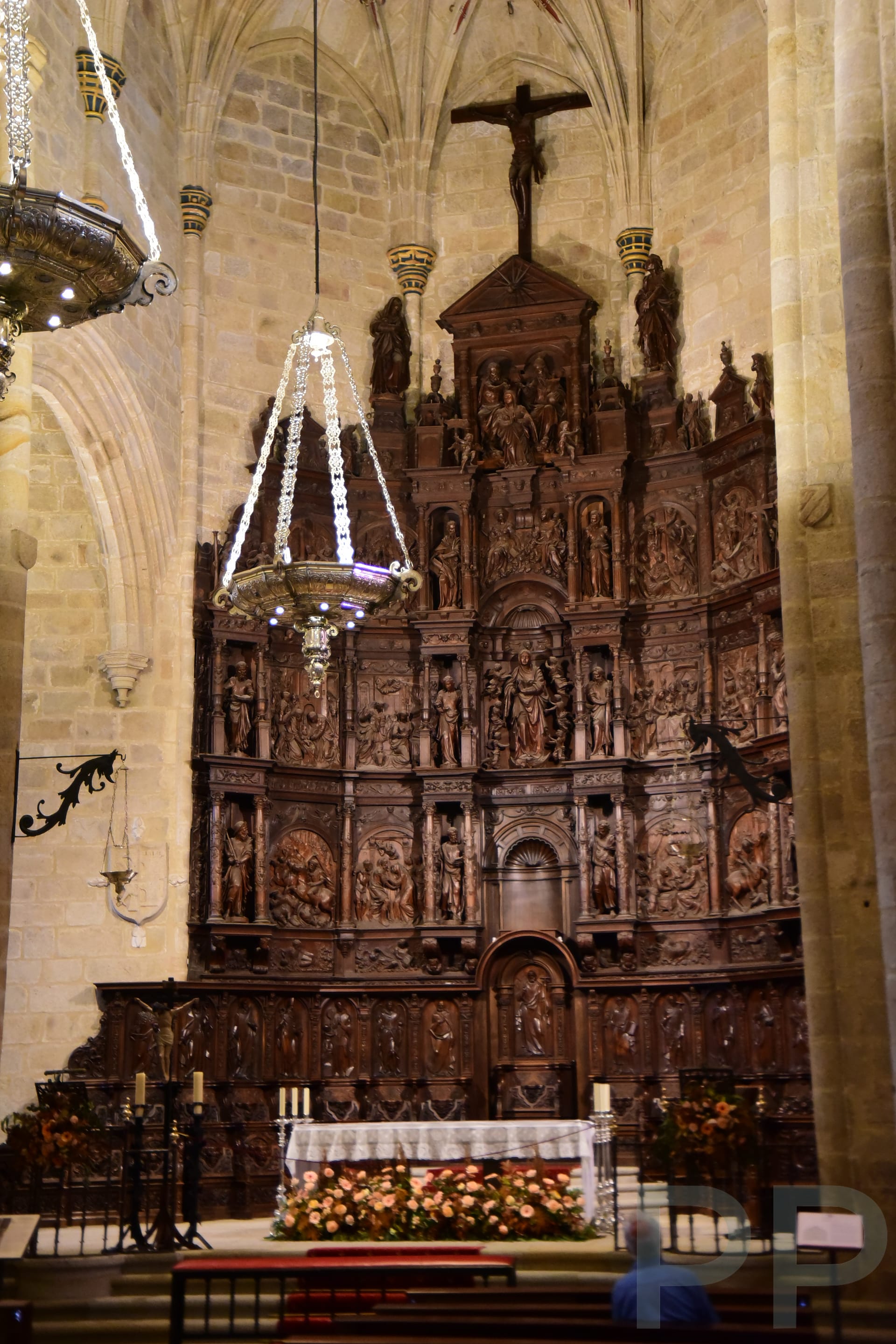 Elaborate gilded altar inside the Concatedral de Santa María in Cáceres, Spain, featuring religious sculptures and detailed carvings.