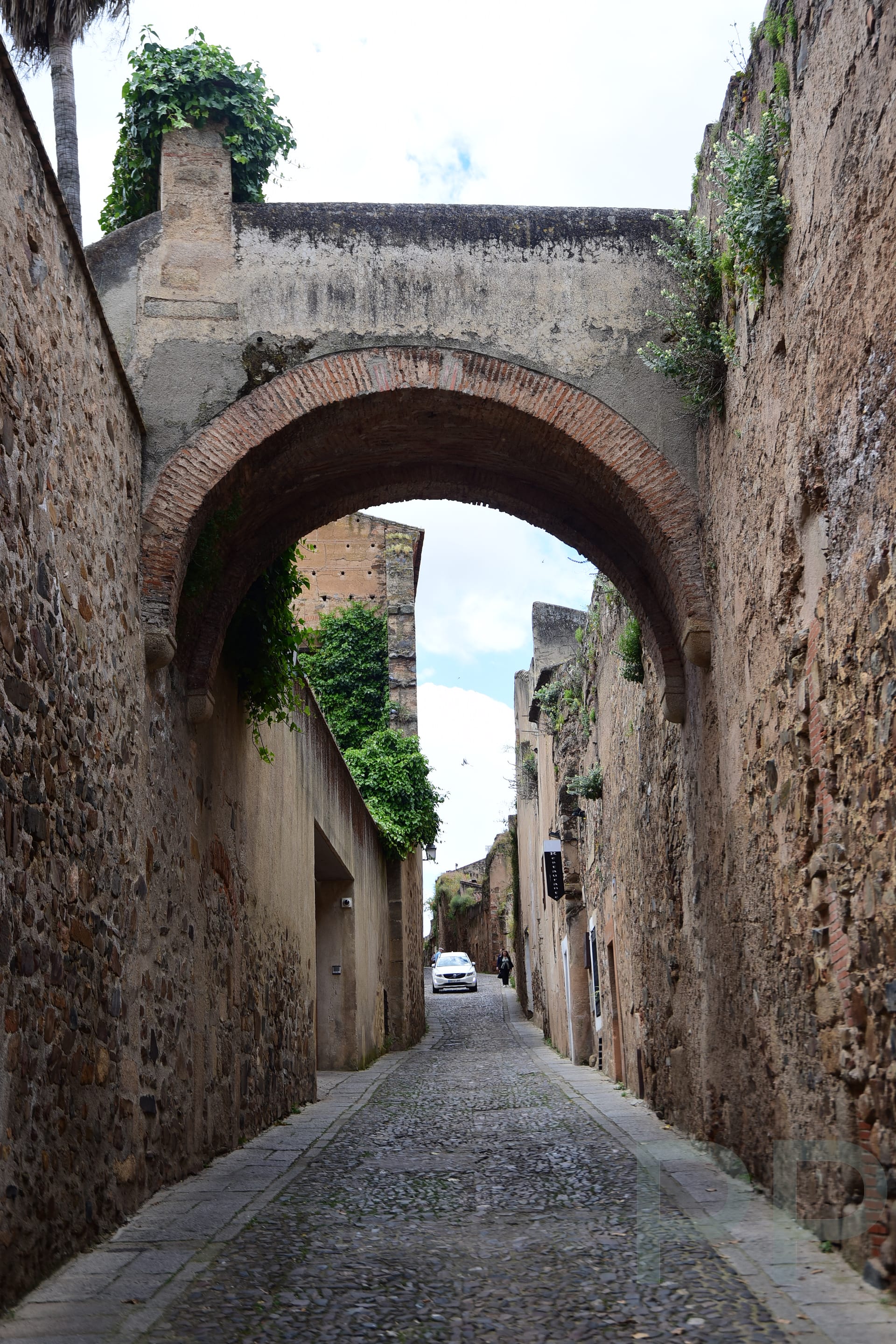 Narrow stone lane with a historic arch overhead in the medieval old town of C&aacute;ceres, Spain, evoking a romantic atmosphere.