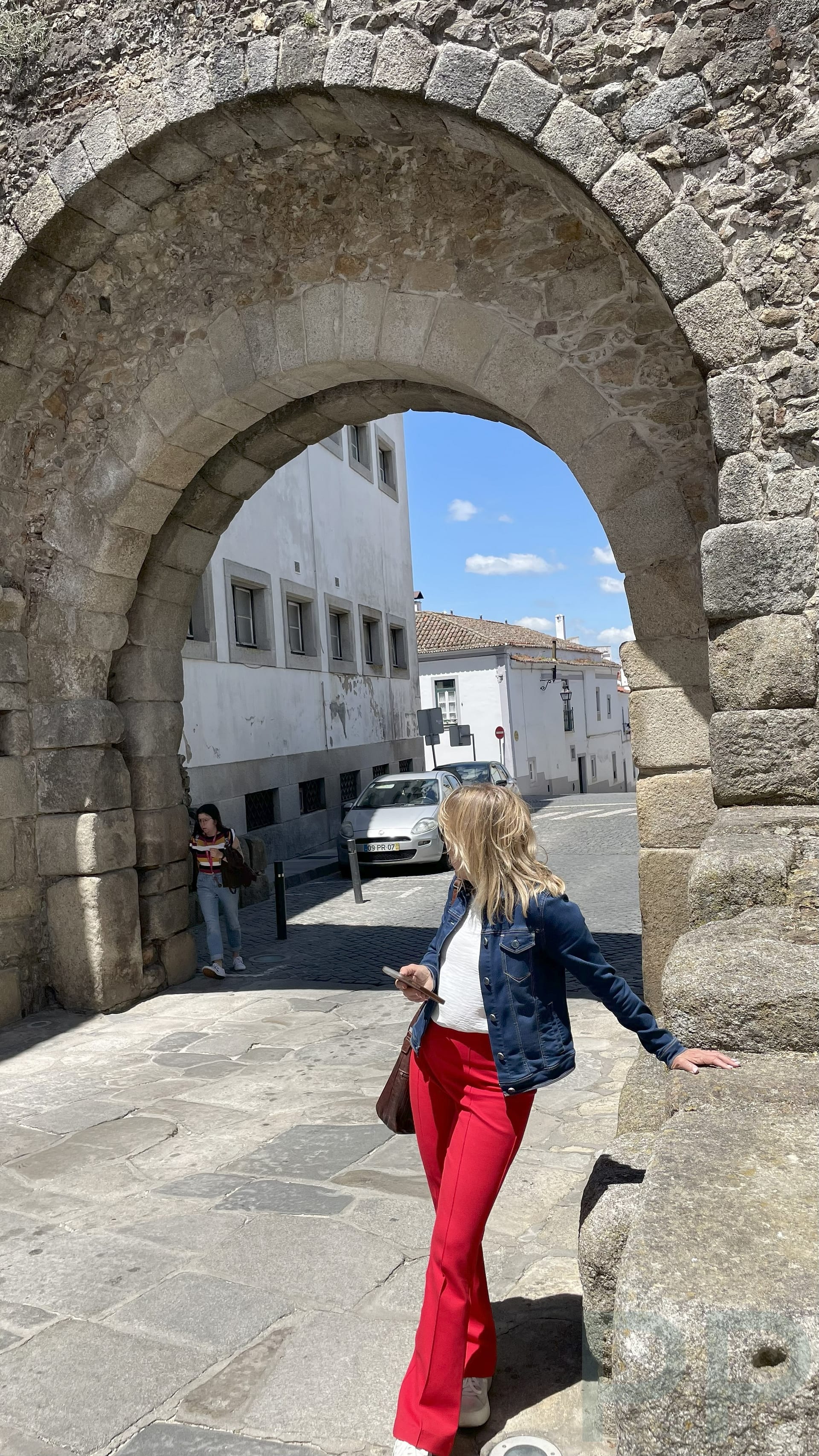 Traveler standing beneath a historic stone archway in Évora, Portugal