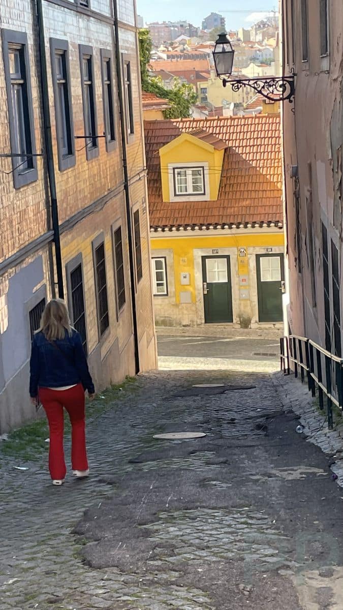 Steep cobblestone street in Lisbon with tiled buildings and narrow lane.