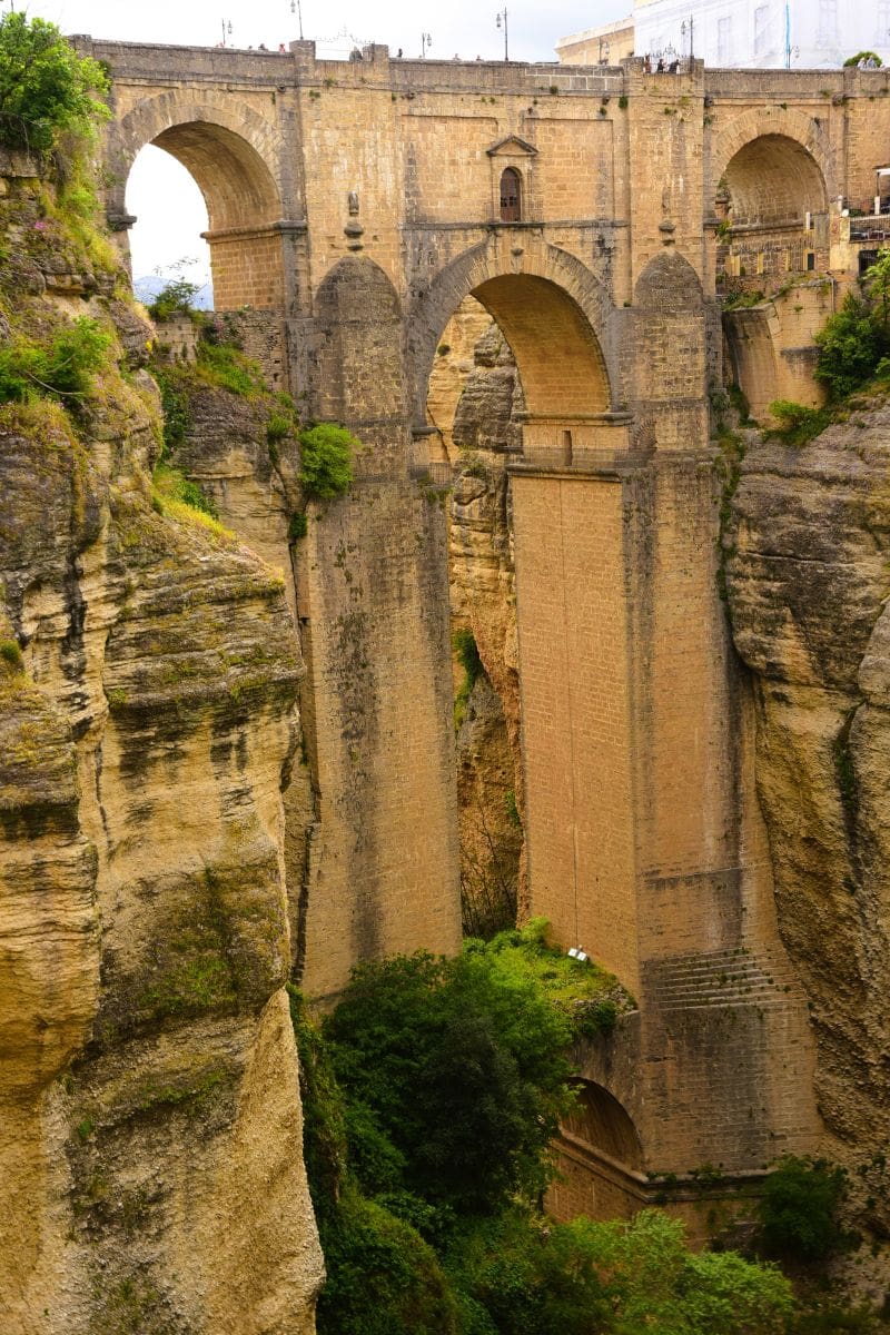 Detailed view of Puente Nuevo&rsquo;s stone arches rising above the deep El Tajo Gorge in Ronda, Spain.