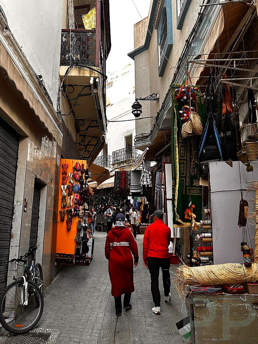 Narrow medina street with people walking in Tangier, Morocco.