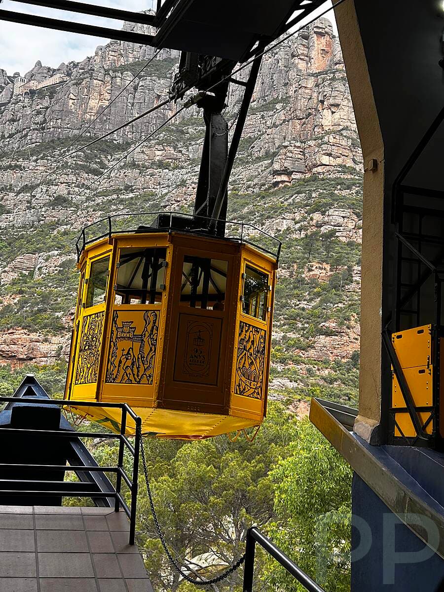 Aeri de Montserrat cable car arriving at the station with rocky cliffs in the background