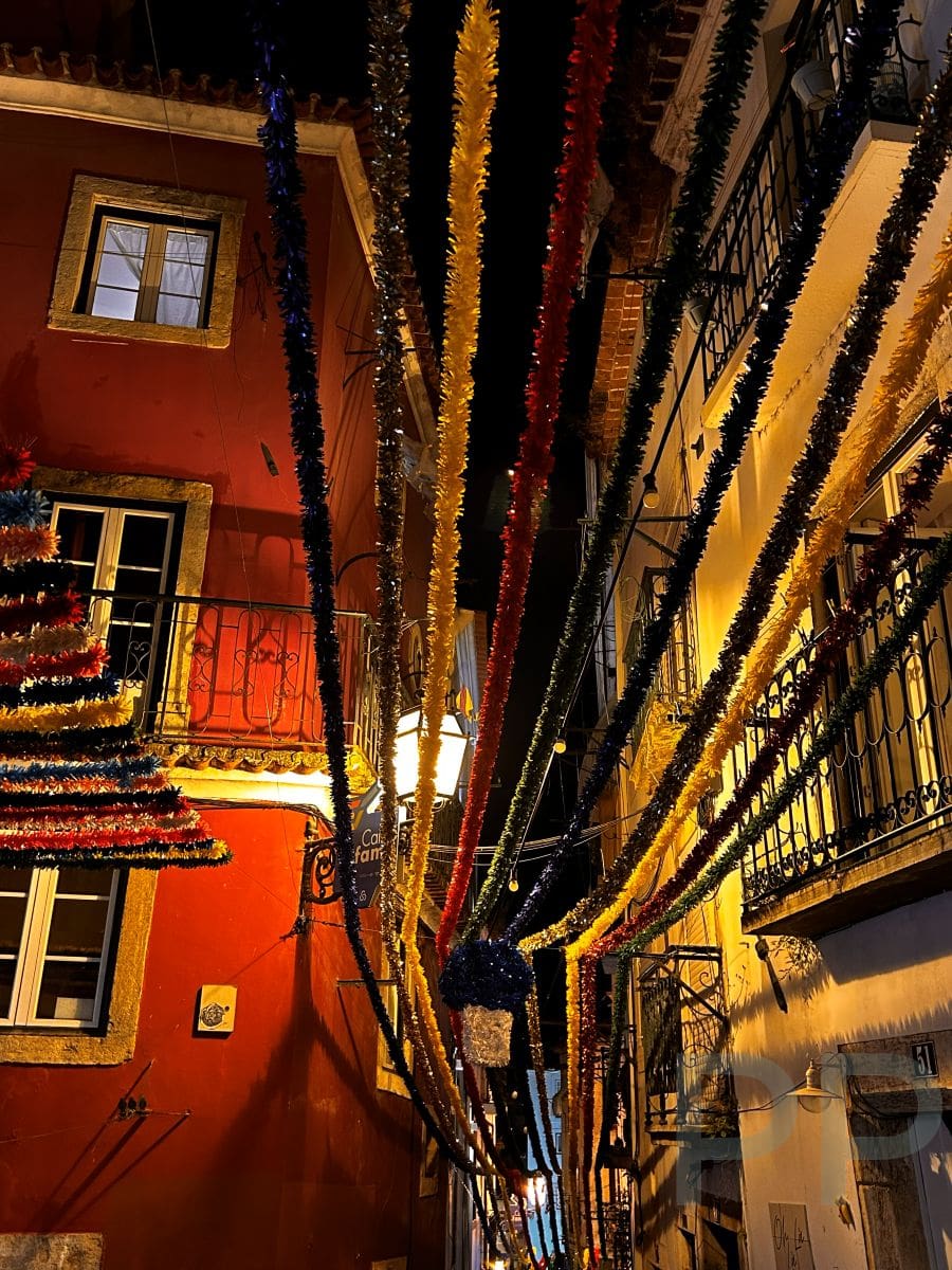 Evening in Alfama with narrow lane lit by warm streetlights.