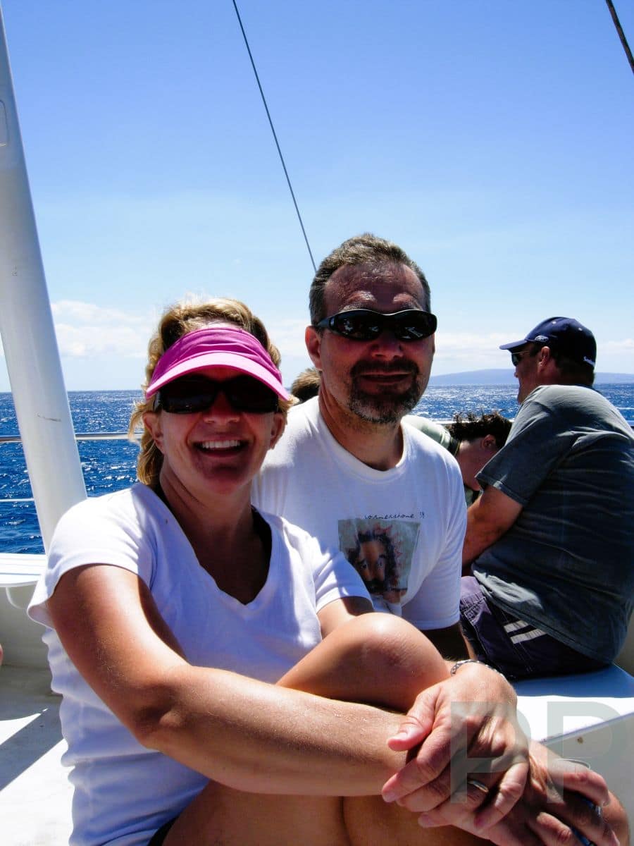 Couple smiling on a boat under bright sun, representing authentic travel experience.